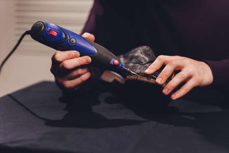 A shoemaker cuts the sole of a Shoe with a shoemakers automatic cutter.