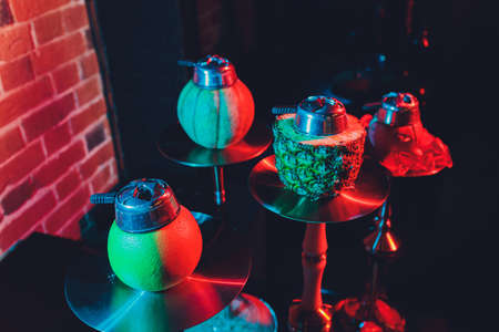 Red shisha hookah with smoke and red sparks on wood table brick, art background. Shisha Concept.