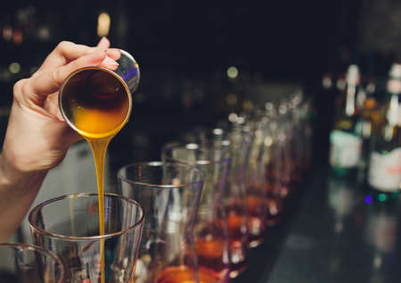 Freshly squeezed carrot juice on a dark background. Juice in a jug of glass, near sticks of carrots and celery. The bartender pours into a tall glass.の写真素材
