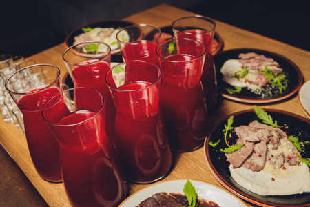 Homemade red wine sangria with orange, apple, strawberry and ice in pitcher and glass on rustic wooden background.の写真素材