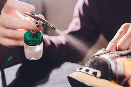 Craft man painting on a pair of shoes. Painting and restoring suede sneakers.の写真素材