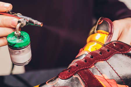 Craft man painting on a pair of shoes. Painting and restoring suede sneakers.の写真素材