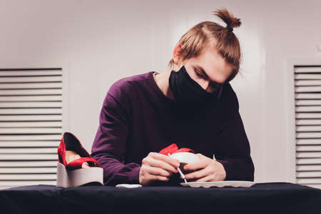 close up cropped photo. man painting with a tip of the brush, focus on the cloth, leather.