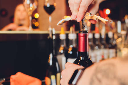 Opening a bottle of wine corkscrew closeup.の写真素材