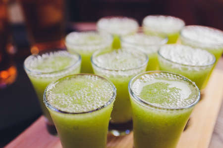 Variation of hard alcoholic shots served on bar counter. Blur bottles on background.の写真素材