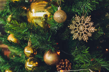 Closeup of christmas fir tree decorated with gold, toys, balls and garland. Traditional winter...