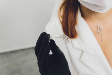 Close-up Of A Womans Hand Putting Transparent Aligner In Teeth.