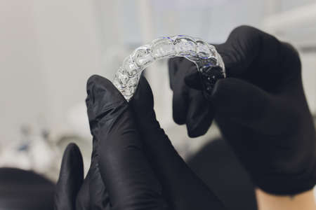 Close-up Of A Womans Hand Putting Transparent Aligner In Teeth.