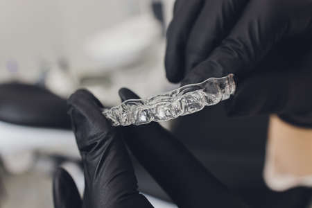 Close-up Of A Womans Hand Putting Transparent Aligner In Teeth.の写真素材