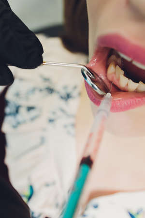 Dentist giving injection for anesthetizing his patient.