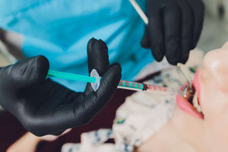 Dentist giving injection for anesthetizing his patient.