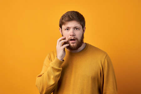 Astonished attractive male has ginger long beard, wonders sudden news, keeps mouth slightly opened,...