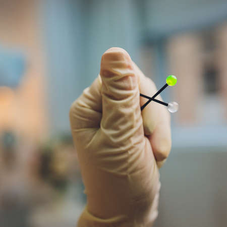 ear jewelry, piercing in hand with a disposable glove.の写真素材