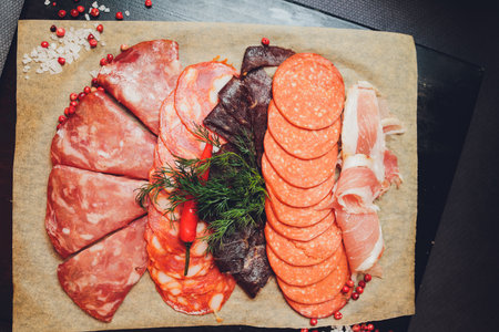 Cutting board with prosciutto, salami, cheese,bread sticks and olives on dark stone background. From top view.の写真素材