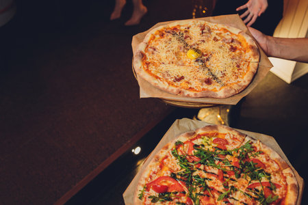 Thin-crust pizza topped with fresh basil leaves. Slices of pizza. Home made food. Italian vegetarian pizza. Concept for a tasty and hearty meal. Rustic wooden background.の写真素材