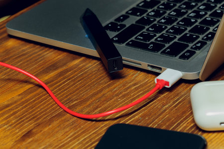 POD e-cigarette or nicotine vapor dispenser being charged in modern laptop with Pods.の写真素材