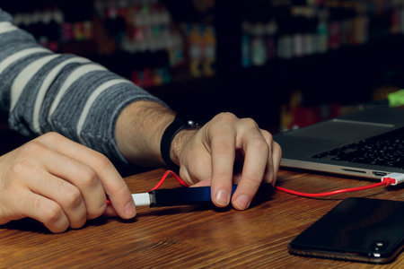 POD e-cigarette or nicotine vapor dispenser being charged in modern laptop with Pods.