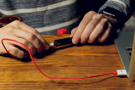 POD e-cigarette or nicotine vapor dispenser being charged in modern laptop with Pods.の写真素材