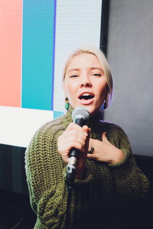 Portrait of a glamorous girl holding a mike and singing.の写真素材