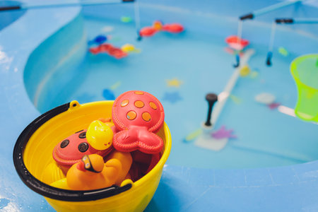 fishing in the paddling pool. Childrens toys in the pool. Toy fish fishing rod. Cheerful children fishing, fishing in the paddling pool.の写真素材
