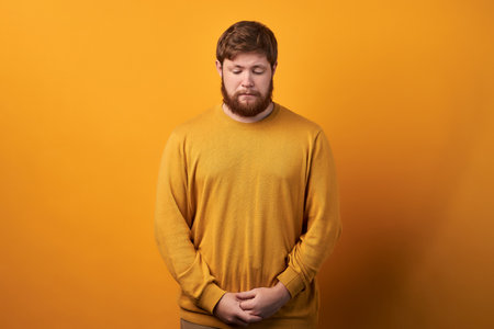 Curious unshaven male worker focused down, looks with interest as notices something, wonders, being...