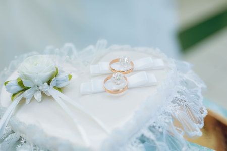 golden wedding rings on decorated little pillow.