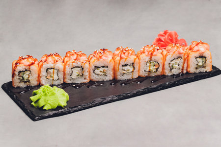 Maki Sushi Rolls with salmon on black stone on dark background. With ginger and wasabi. Sushi menu. Japanese food. Closeup of delicious japanese food with sushi roll. Horizontal photo.の写真素材
