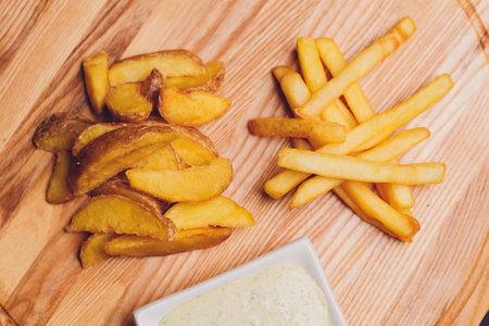 fried French fries on a plate on the wooden table.