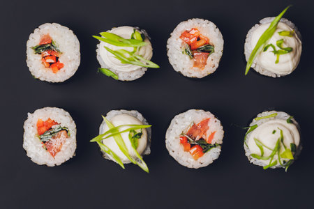 Maki Sushi Rolls with salmon on black stone on dark background. With ginger and wasabi. Sushi menu. Japanese food. Closeup of delicious japanese food with sushi roll. Horizontal photo.の写真素材