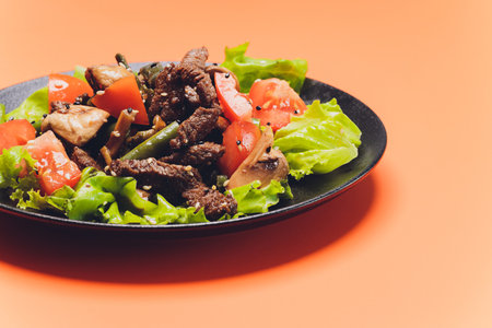 steak with vegetables on the orange background.の写真素材