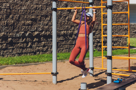 Motivated, concentrated athletic woman doing sports, training , exercising with rubber expander...