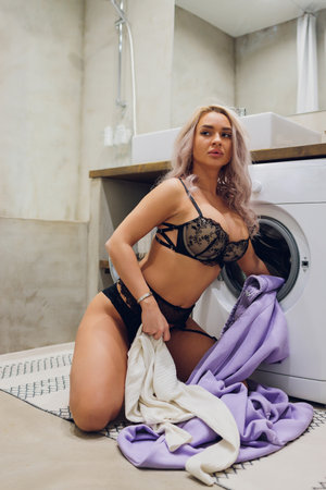 woman in underwear in the bathroom with washing machine.の写真素材