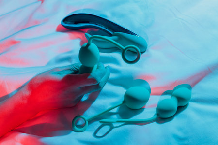 Woman holding anal balls in bed close-up.