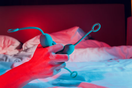 Woman holding anal balls in bed close-up.の写真素材