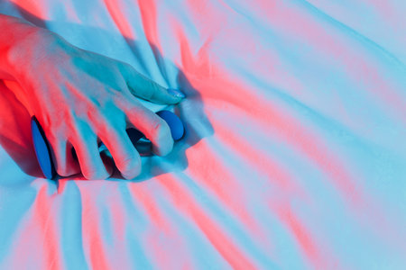 Woman holding anal balls in bed close-up.