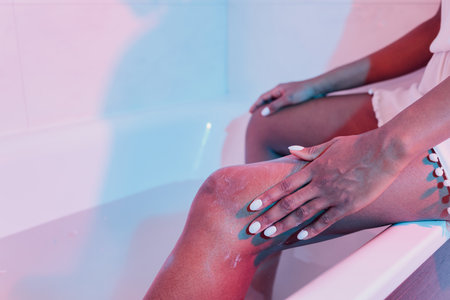 A woman applying moisturiser to her legs close-up.の写真素材