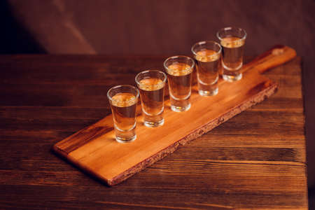 Variation of hard alcoholic shots served on bar counter. Blur bottles on background.の写真素材