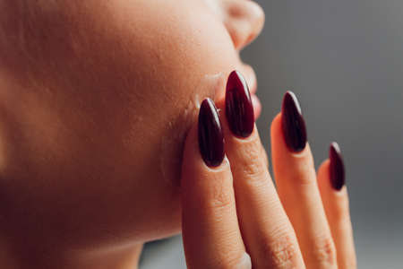 Closeup up of a young woman applying beauty product.の写真素材