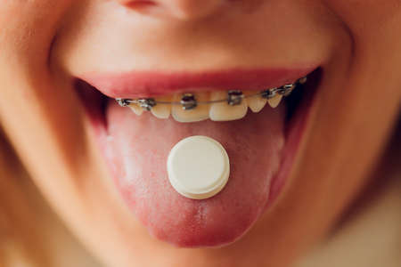 Taking pills. Woman taking pill - closeup of tongue.の写真素材