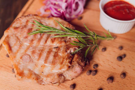Beef steak with twig rosemary on a wooden table.の写真素材