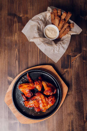 Chicken wings on white plate with sauce on wooden table. Low angle.の写真素材