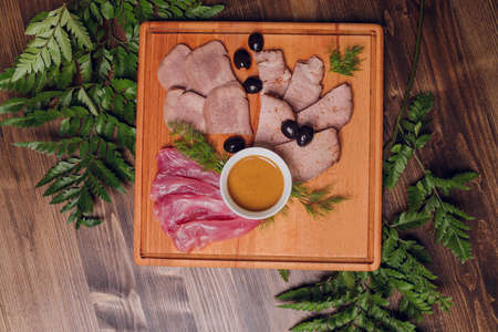 Cold meat on cutting board on wooden table. Ham, salami, sausage mortadella and turkey.の写真素材
