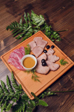 Cold meat on cutting board on wooden table. Ham, salami, sausage mortadella and turkey.の写真素材