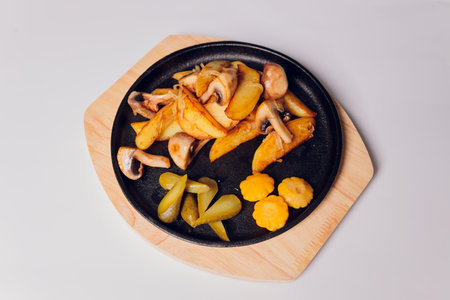 fried potatoes with mushrooms in a pan on a white background.の写真素材