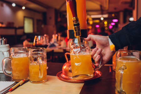 The male bartender pouring beer into a glass close-up. Street food. A glass with cold beer in the...
