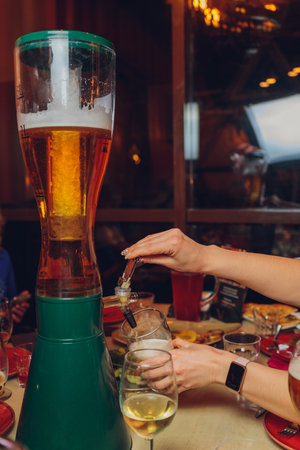 The male bartender pouring beer into a glass close-up. Street food. A glass with cold beer in the bartender s hands.の写真素材
