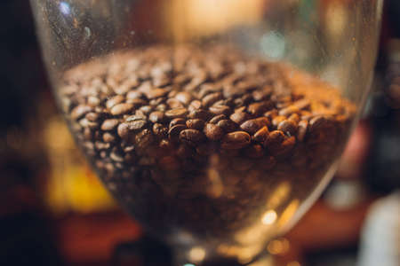 Glass bank with coffee grains costs on a table on a black background.