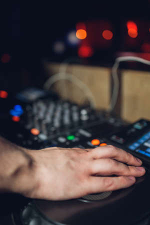 The DJs hand on the mixer. Dj on the turntables. hand on a mixer close-up. Girl Man DJ at the mixer remote.の写真素材