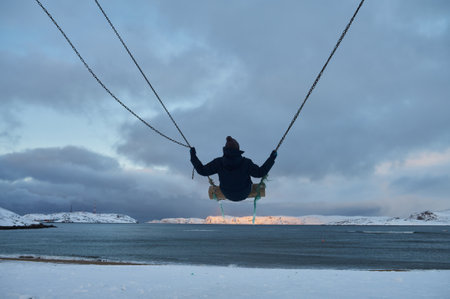 Beautiful woman with cup of tea on Swing. River on background, nature and calm. Self isolation.の写真素材