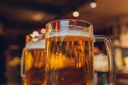 Glass of light beer on a dark pub.